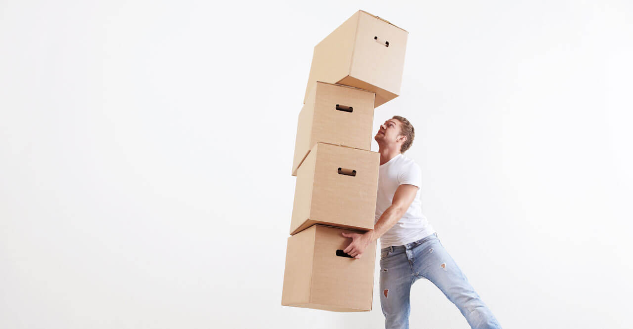 A photo of man trying to carry lots of boxes